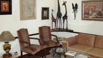 Ein Wohnzimmer mit Leopardenmuster-Sesseln, einem Glastisch, einer Couch und einer Lampe.