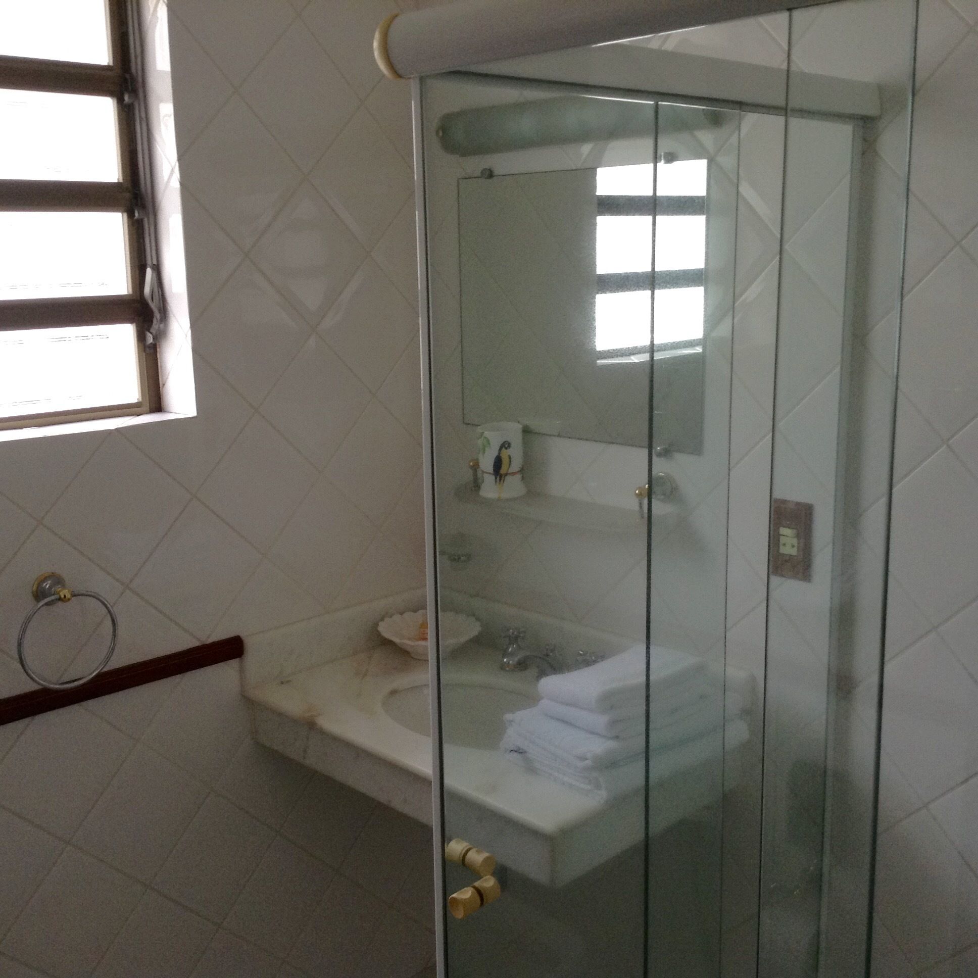 A bathroom with a glass-enclosed shower, a sink, and a mirror.