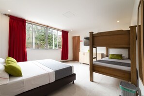 A room with a bed, a bunk bed, a window with red curtains, a wooden cabinet, and a television. - Ayenda 1238 Nuevo Colombia (Medellín)