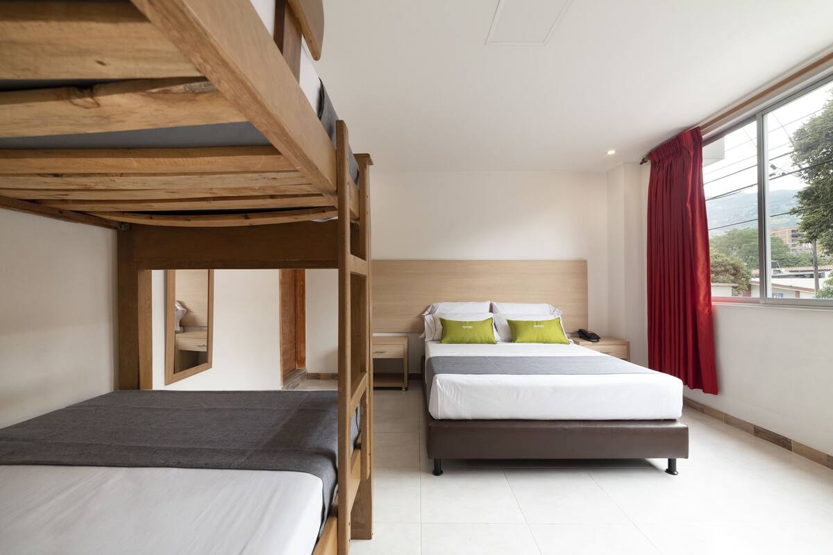 A bedroom with bunk beds, a bedside table, a nightstand, and a window with curtains.