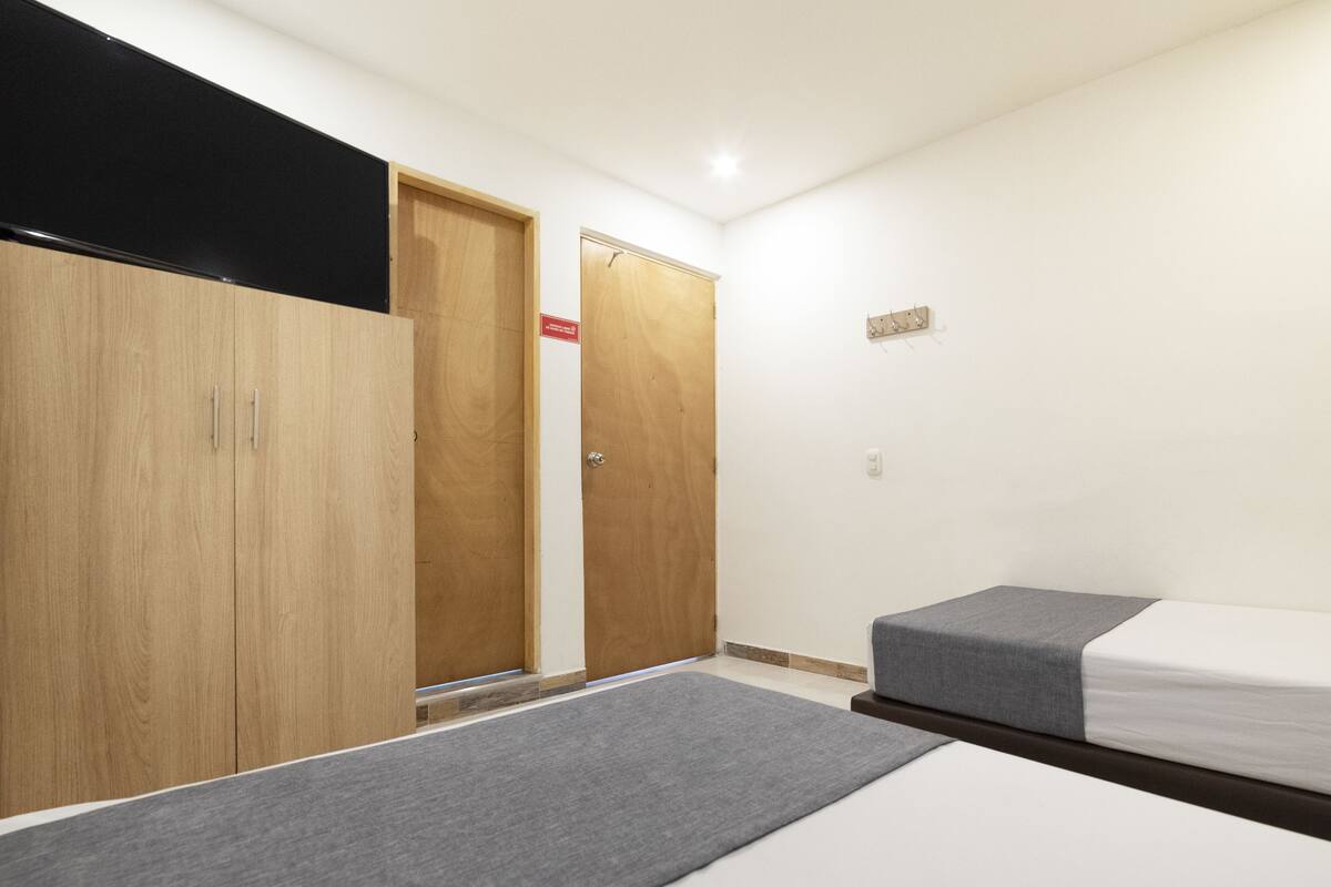 A bedroom with two single beds, a wooden wardrobe, and a small desk.