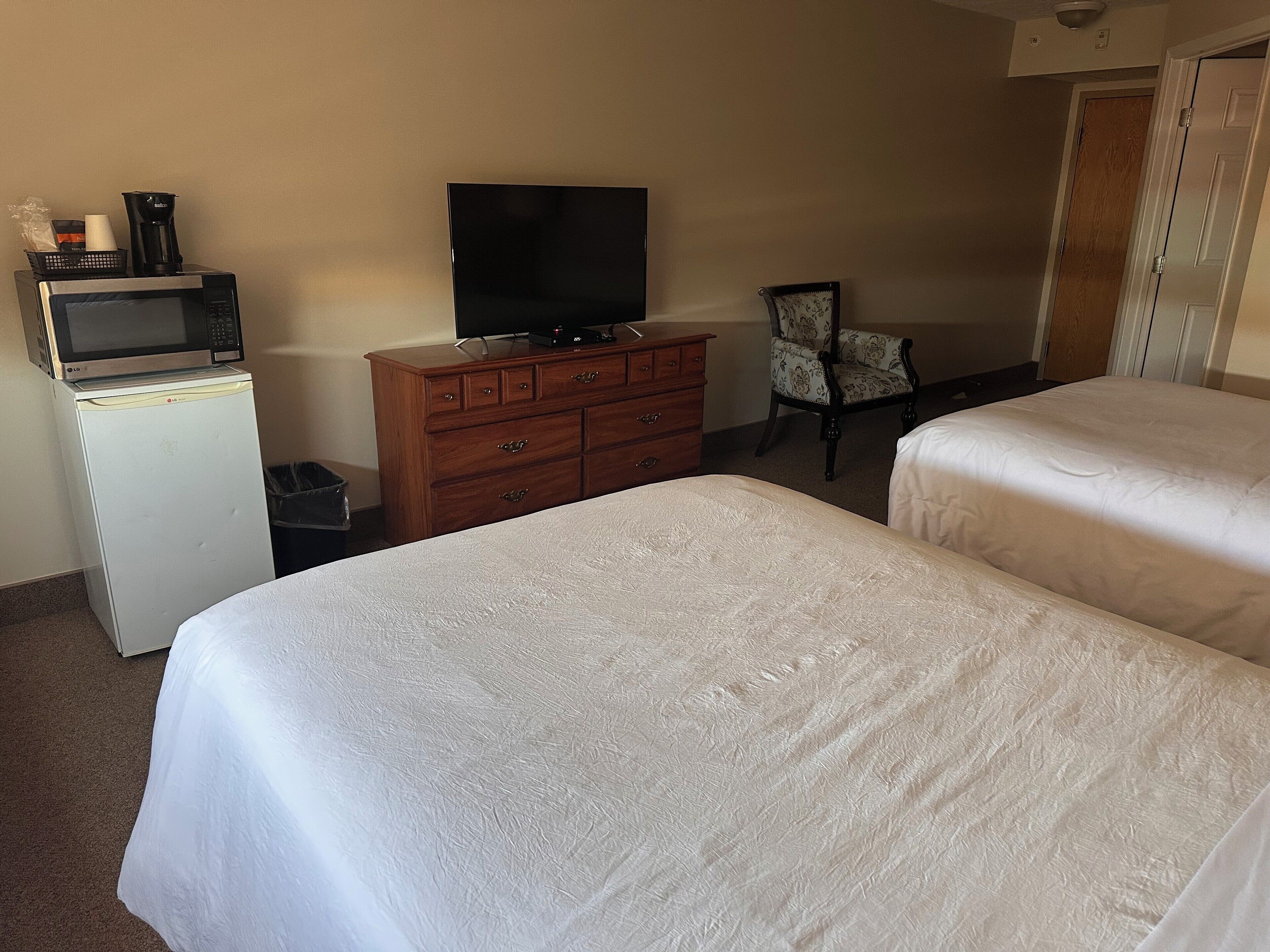 Una habitación de hotel con dos camas, un aparador de madera, un televisor y un microondas.