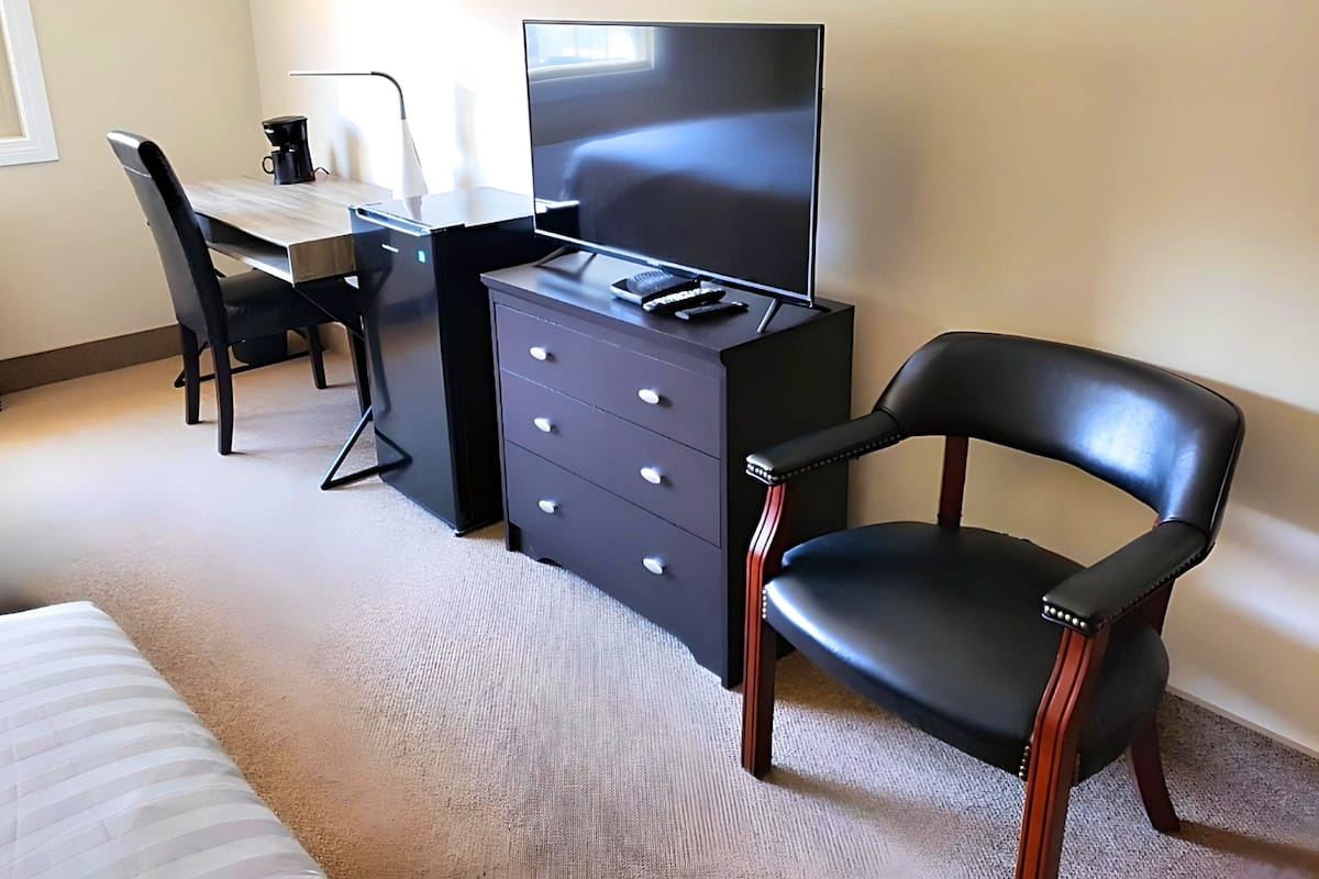 Een hotelkamer met een bed, een bureau met een computer, een stoel en een televisie.