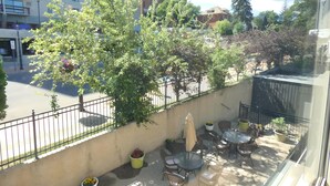 Un balcon avec des sièges d’extérieur, une vue sur une rue de la ville et un bâtiment sur lequel on peut lire l’inscription « TULIS ».