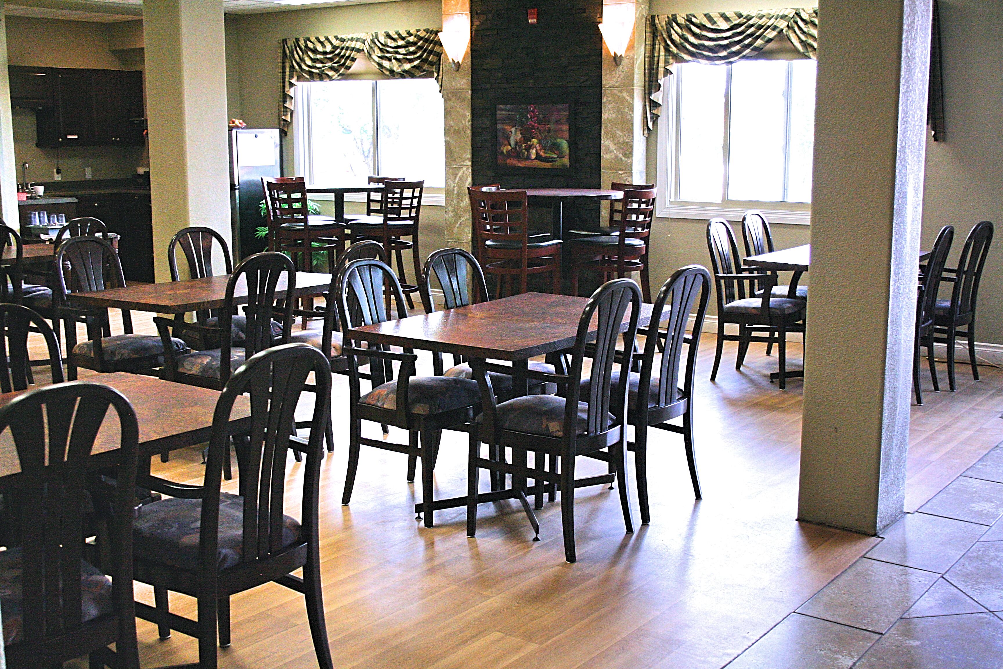Un grand espace à manger avec plusieurs tables et chaises, une cuisine  à l’arrière-plan et une cheminée.