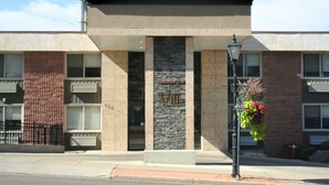 Un bâtiment à la façade en pierre, une enseigne indiquant « Villa » et un panneau interdisant le stationnement.