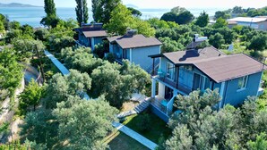 A modern house with a balcony, surrounded by lush greenery and overlooking a body of water. - Adasu Otel (Marmara)