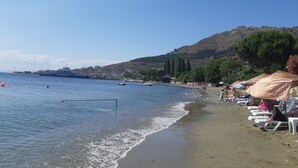 A beach with a clear sky, calm sea, and a mountainous backdrop. - Adasu Otel (Marmara)