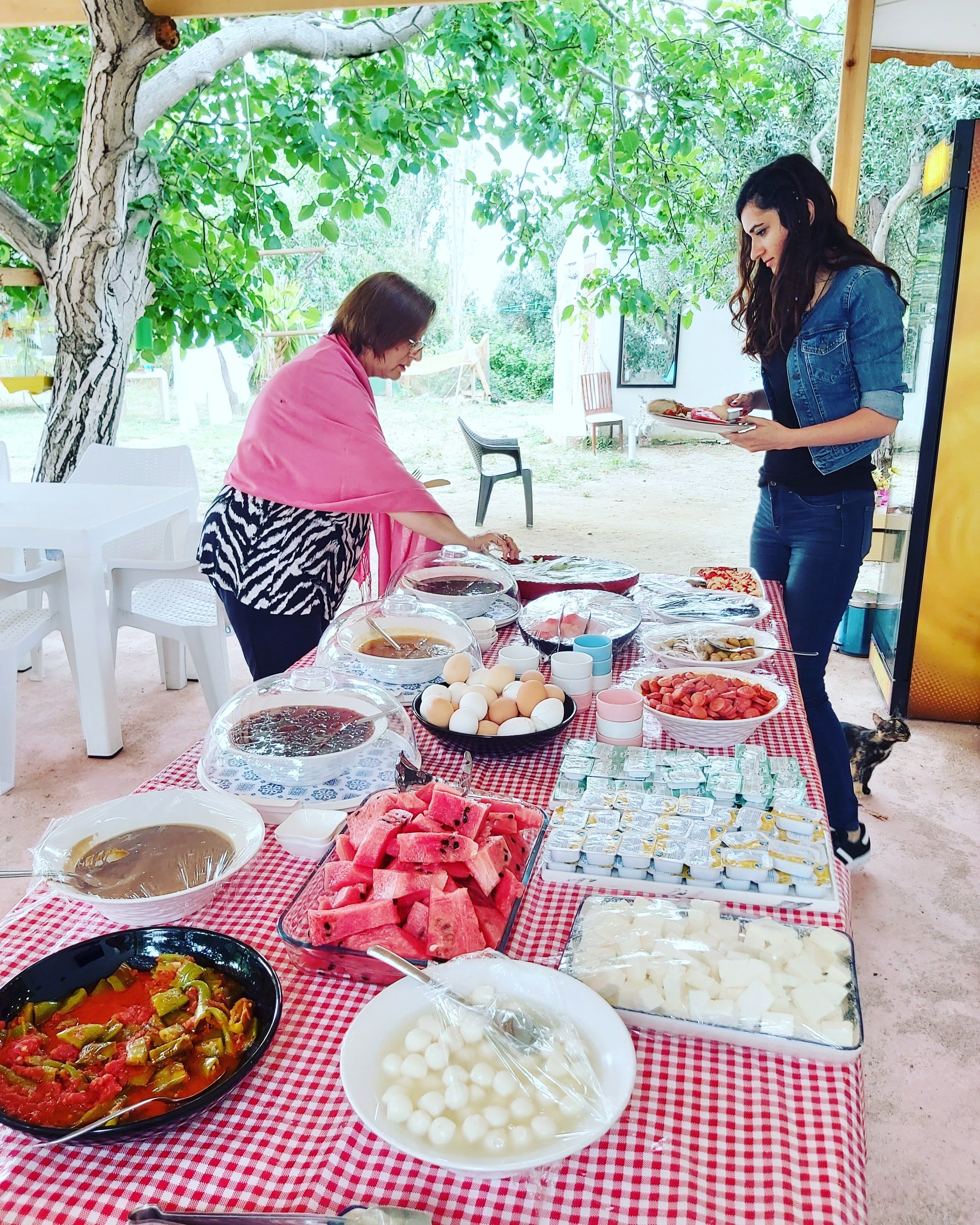 An outdoor dining area with a variety of food items and a checkered tablecloth.