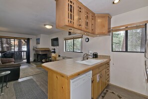Une cuisine moderne avec des meubles en bois, un lave-vaisselle et une grande fenêtre.