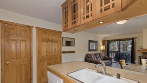 Una cocina con armarios de madera, lavavajillas y un amplio ventanal.