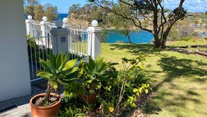 Un jardín con plantas en macetas, una cerca blanca y vista al mar.