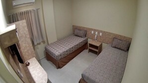A compact hotel room with two single beds, a small table, a built-in shelf, and a wall-mounted air conditioner. - Pousada Cangaço (Santana Do Ipanema)