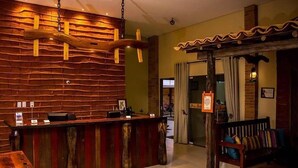 A reception area with a wooden reception desk, a bench, and a wall with a wooden plank design. - Pousada Cangaço (Santana Do Ipanema)