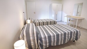Un dormitorio con dos camas, un escritorio, una silla y un armario.