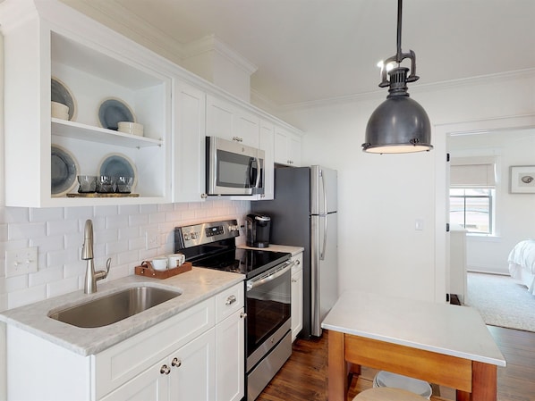 A modern kitchen with white cabinetry, stainless steel appliances, a marble countertop, and a pendant light. - Heated Pool Access | 5*Clean | Flex Cancelation (Savannah)