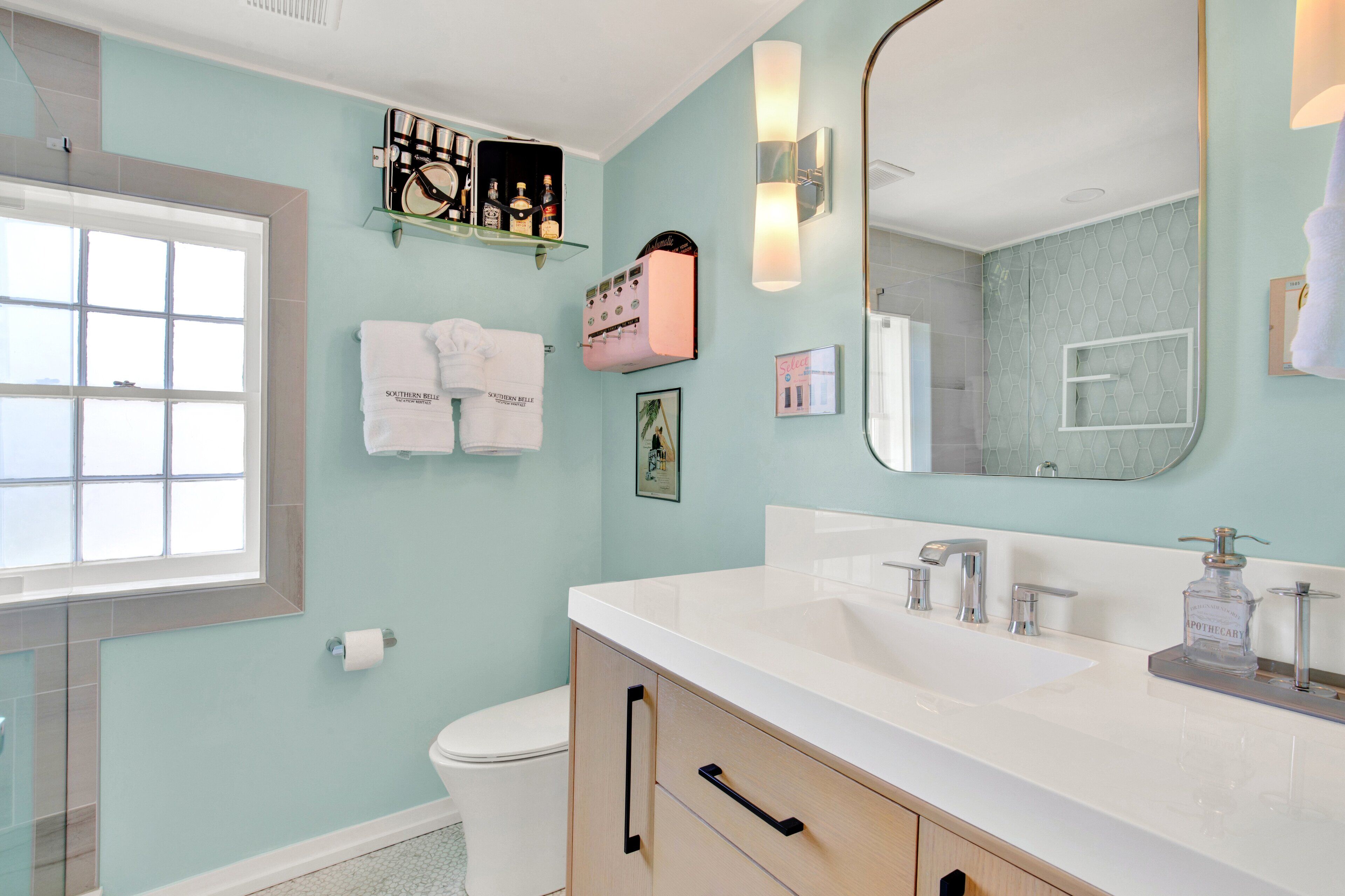 A bathroom with a large mirror, white sink, and a glass shower enclosure.