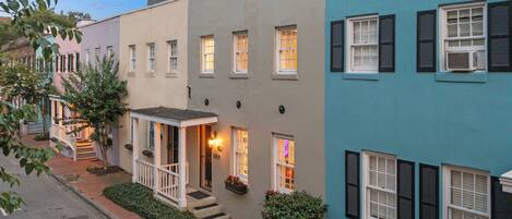 A row of townhouses with a front porch, steps, and a small garden area.