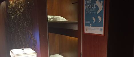 A bunk bed room with a poster on the wall and a lamp on a table.