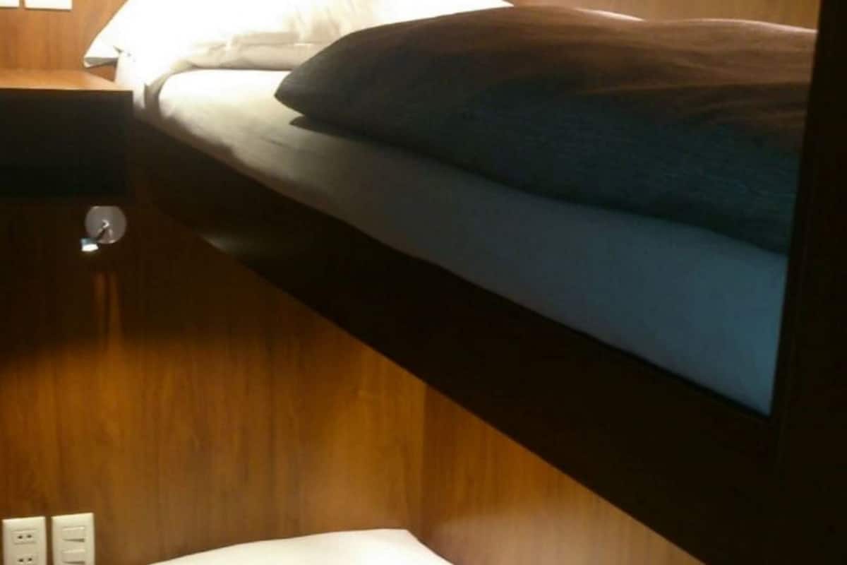 A bunk bed room with wooden walls and a small bedside table.