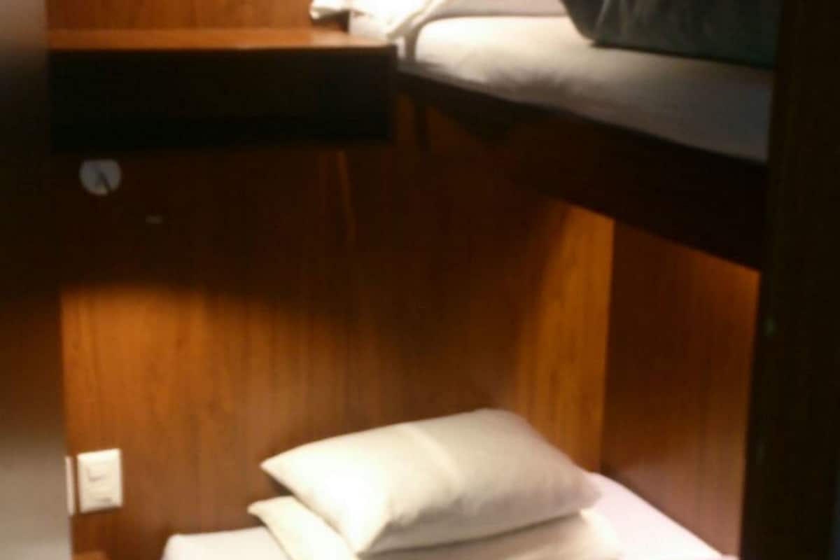 A bunk bed with wooden walls and a small bedside table.