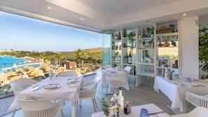 Un espace repas avec des tables préparées pour deux personnes, offrant une vue sur une piscine et un paysage pittoresque.
