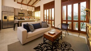 A spacious living area with a sofa, coffee table, and a view of the kitchen and balcony. - Oceanfront•Sleeps 6•Full Kitchen•BBQ•Pool•Balcony - Alouatta Guesthouse (Las Catalinas)