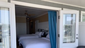 A bedroom with two beds, a ceiling fan, and a view through an open door. - Ballard's (Block Island)