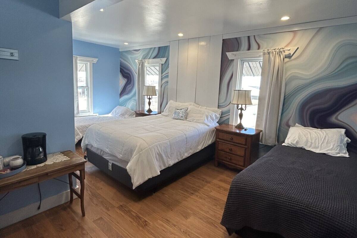 A bedroom with two beds, a wooden nightstand, a coffee maker, and a mirror.