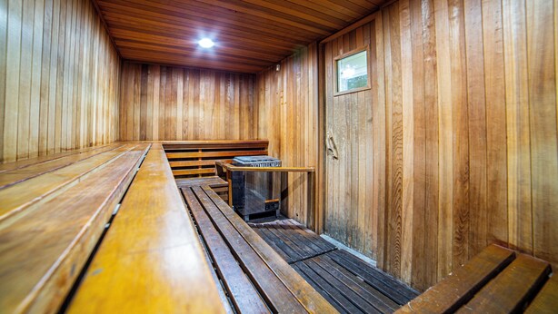 Eine Sauna mit Holzbänken und einem Hocker-Heizgerät.