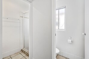Une salle de bain avec une douche, des toilettes et une fenêtre.