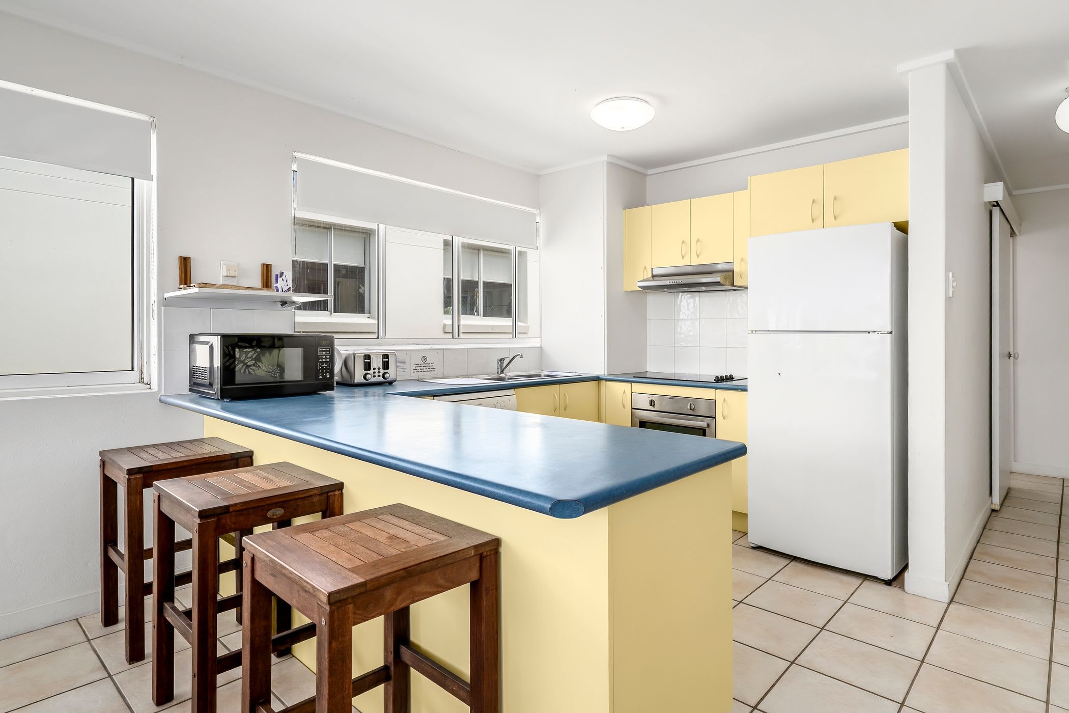 Une cuisine moderne dotée d’un îlot central, de tabourets de bar, d’un four à micro-ondes, d’une cuisinière et d’un réfrigérateur.