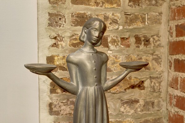 A statue of a woman holding scales, set against a brick wall background. - Heated Pool Access | 5*Clean | Flex Cancelation (Savannah)