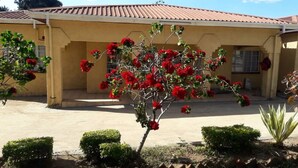 Una casa con tejado de baldosas y un pequeño jardín con flores rojas.