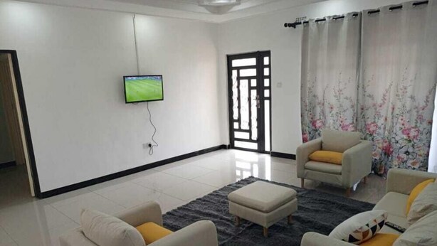Una sala de estar moderna con dos sofás, una mesa de centro y un televisor de pantalla plana montado en la pared.