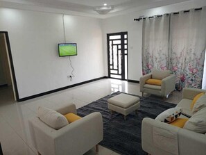 A modern living room with two sofas, a coffee table, and a flat-screen TV mounted on the wall.
