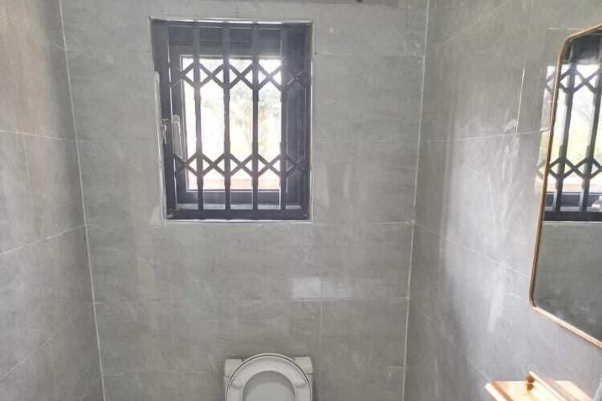 A small, modern bathroom with a toilet, sink, and a window with bars.