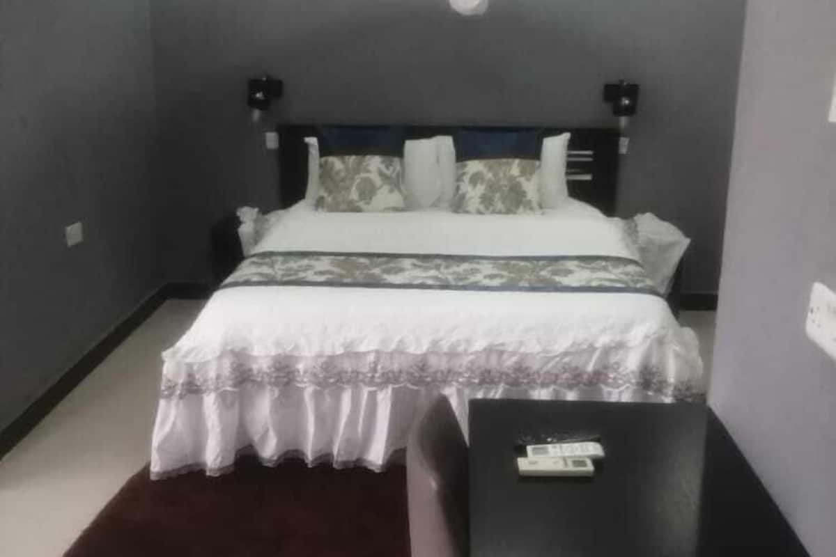 A bedroom with a bed, bedside tables, a desk, and a hanging light fixture.