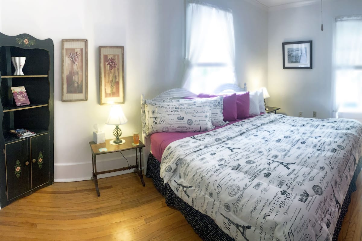 A bedroom with a bed, bedside tables, a chair, and a wardrobe.