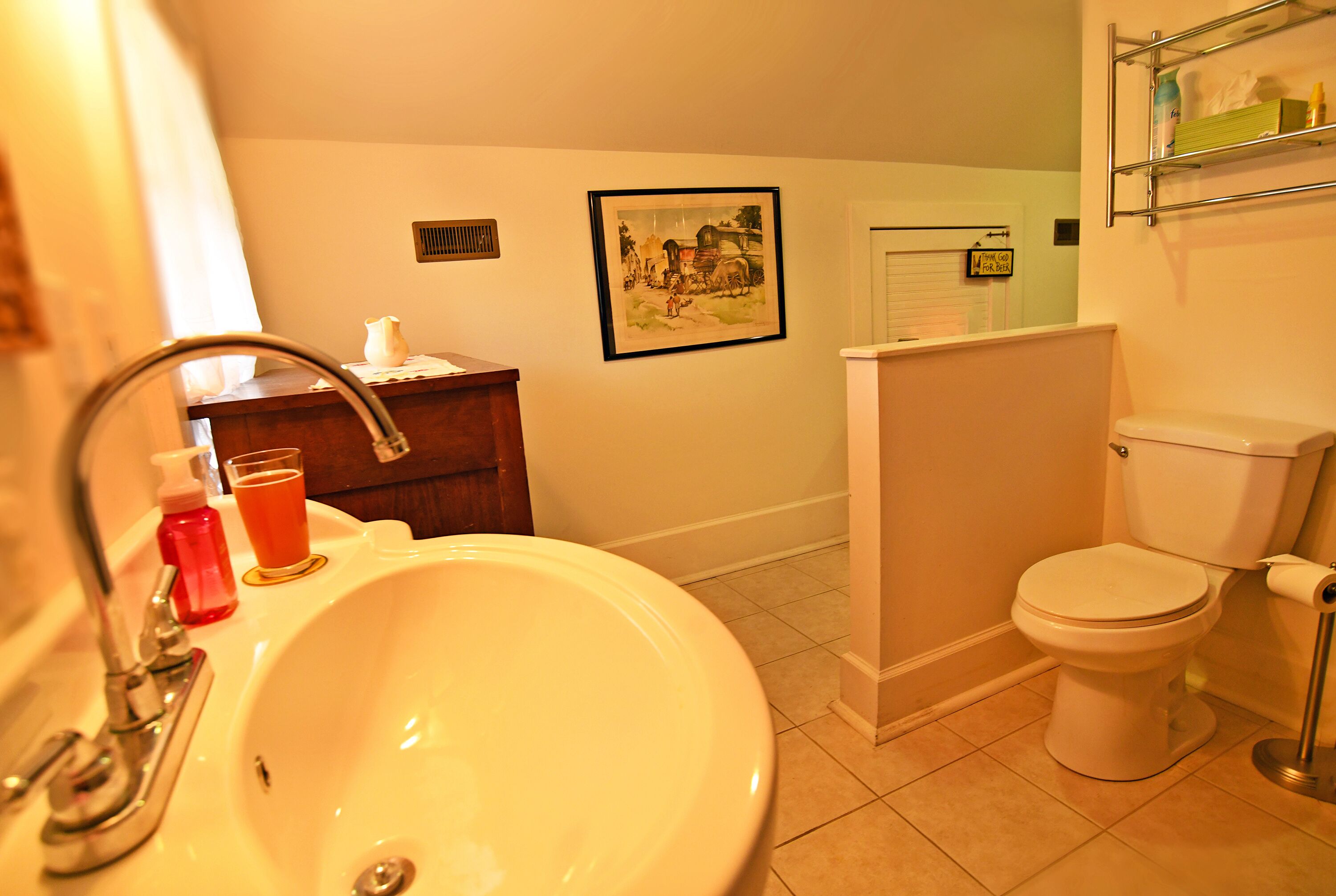 A bathroom with a sink, toilet, and a framed picture on the wall.