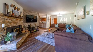 A living room with a fireplace, a television, a sofa, and a coffee table. - Walk to Ski LIft, 2 Master Suites WIFI & Garage (Mammoth Lakes)