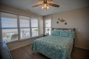Ein Schlafzimmer mit Bett, Deckenventilator und Blick durch das Fenster.
