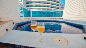 A hot tub with two glasses of beer on a white deck, overlooking a large cruise ship. - Hermosa Casa Playera (Cartagena)