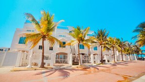 A beachfront hotel with white architecture, palm trees, and a clear blue sky. - Hermosa Casa Playera (Cartagena)