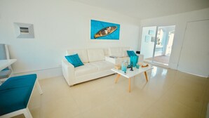 A modern living room with a white sofa, a coffee table, and a blue artwork on the wall. - Hermosa Casa Playera (Cartagena)