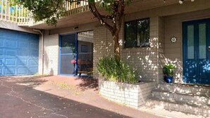 A residential building with a garage door, a front door, and a small garden area with plants.