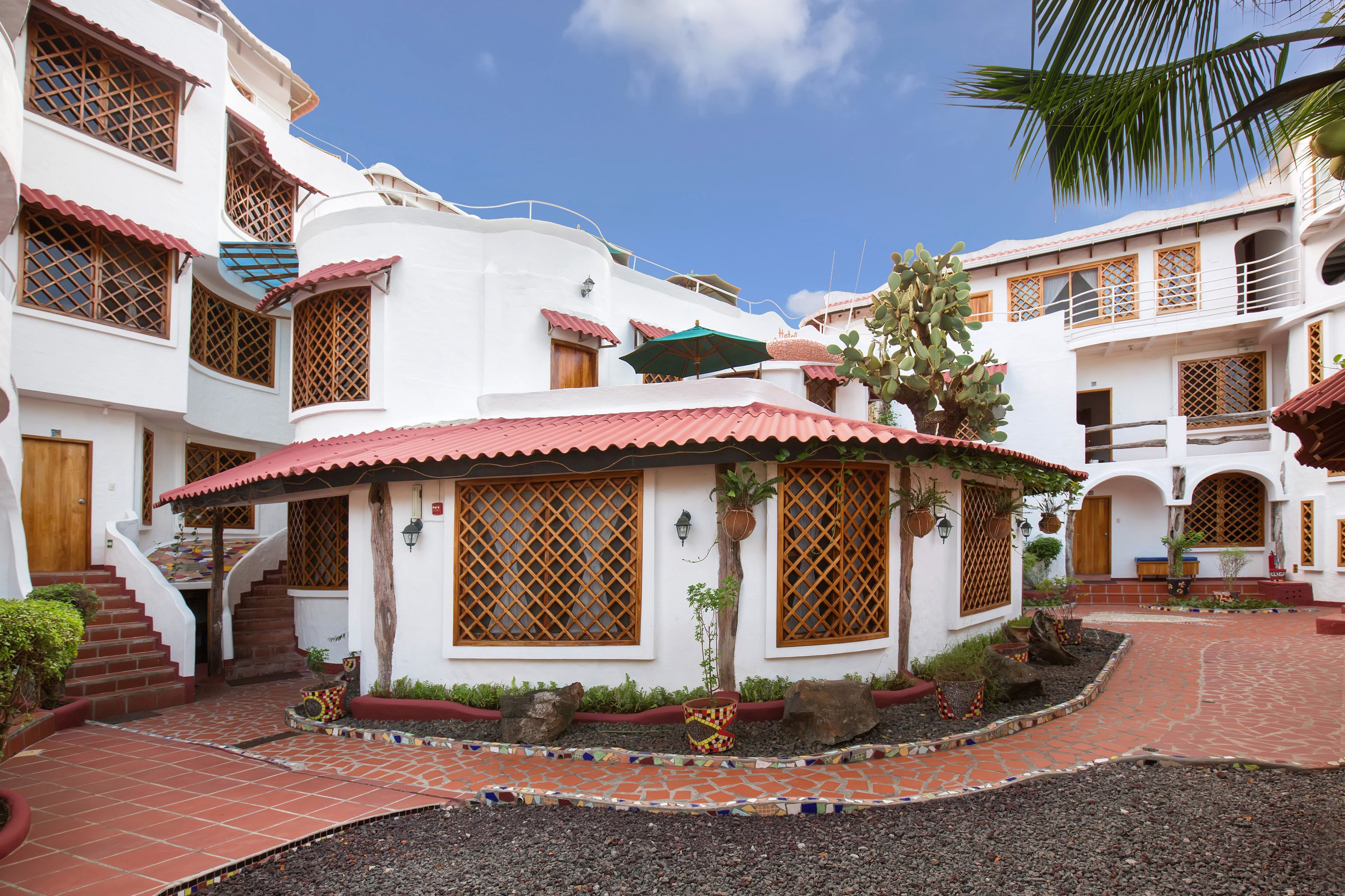A courtyard with a tiled floor, a central seating area, and a staircase leading to an upper level.