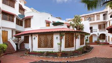 A courtyard with a tiled floor, a central seating area, and a staircase leading to an upper level.