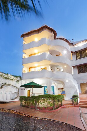 A multi-story building with balconies, a tiled entrance, and a small garden area. - Mainao (Puerto Ayora)