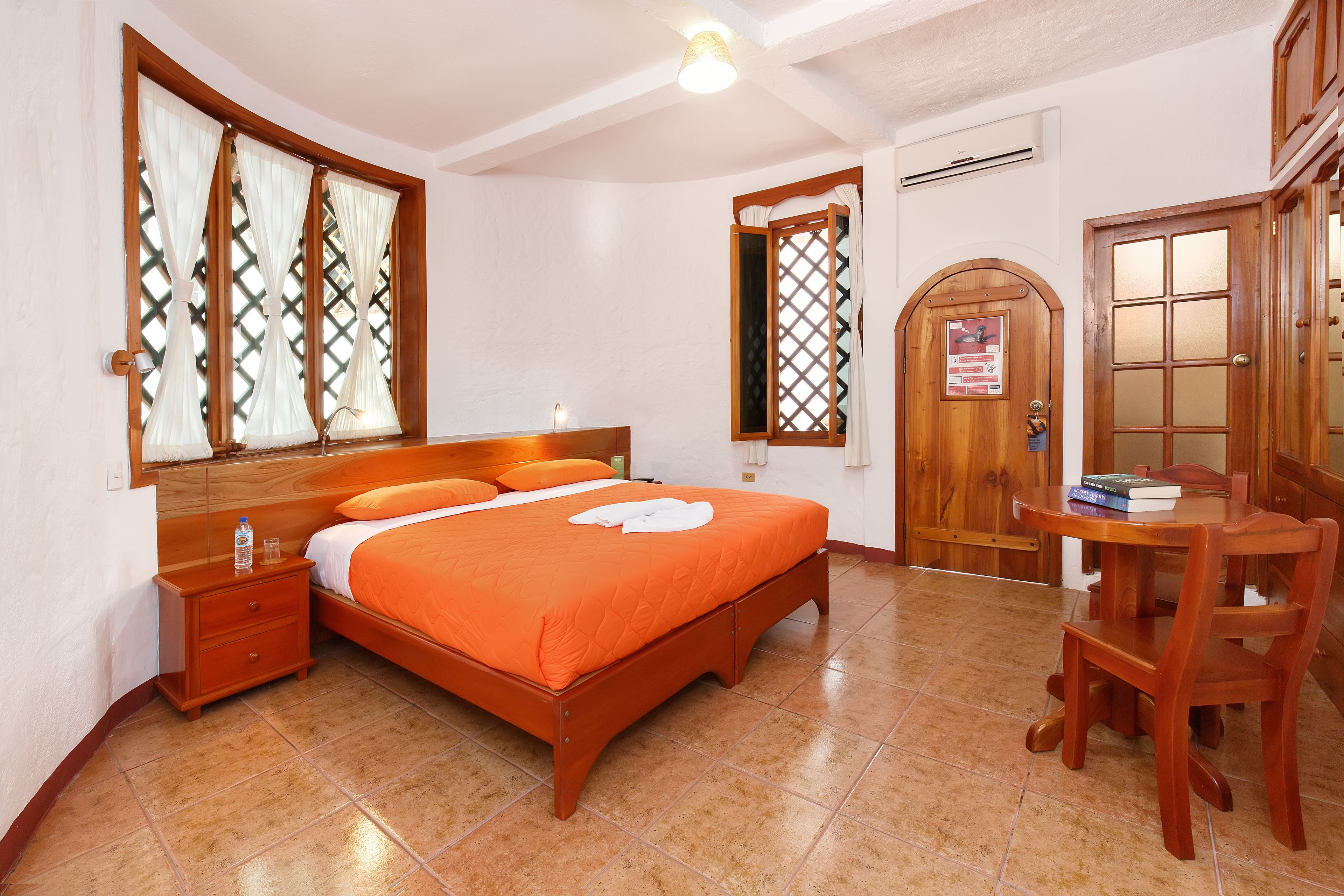 Un dormitorio con una cama de madera, una mesita de noche, una silla de madera y una puerta de madera con un ventanal.